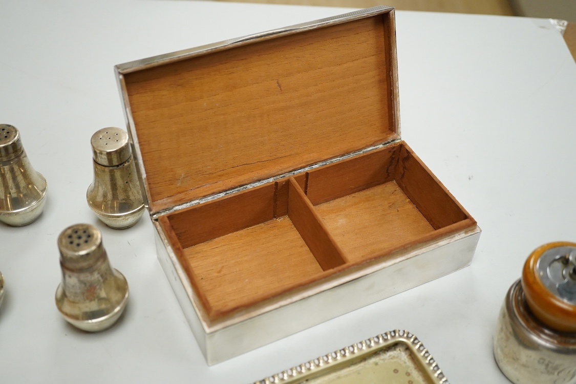A George V engine turned silver mounted rectangular cigarette box, Birmingham, 1923, 17.7cm, a sterling mounted pepper grinder, four weighted sterling condiments and a small plated tray.
